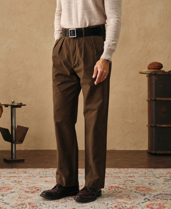Brown two-pleated chino pants worn with belt, straight leg and cuffed hem