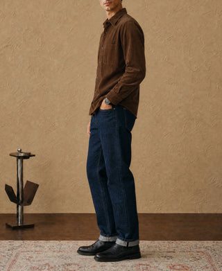 Brown corduroy work shirt in side profile with blue jeans and boots