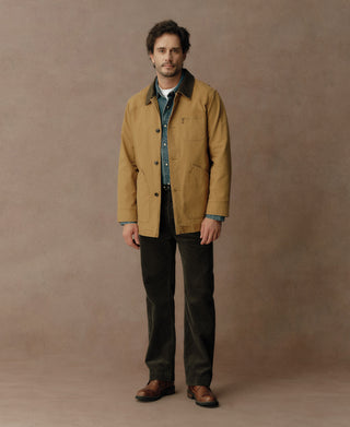Khaki canvas field jacket with dark collar, button front, and chest pocket, shown worn.