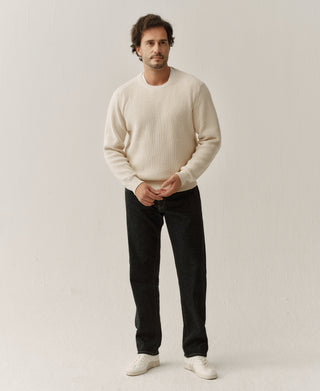 Model wearing a natural cotton crewneck sweater with ribbed cuffs and hem