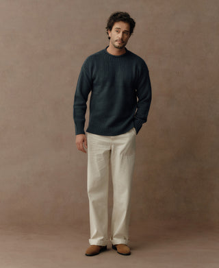 Dark blue wool sweater with textured chest panels, ribbed cuffs, and hem, worn with trousers