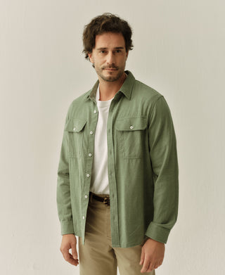 Man wearing sage green work shirt with button-front, pointed collar, and chest pockets.