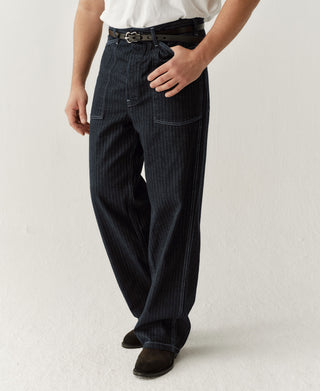 Indigo herringbone denim fatigue pants, side view with buckle belt and slant pockets
