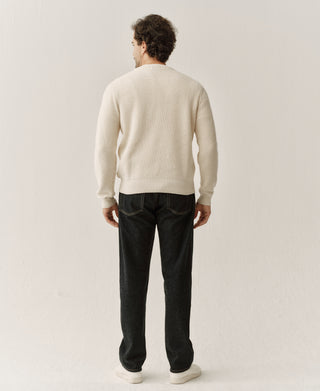 Natural cotton knit sweater shown from the back, with ribbed cuffs and hem.